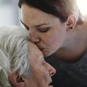 jüngere Frau küsste einer älteren Frau auf die Stirn