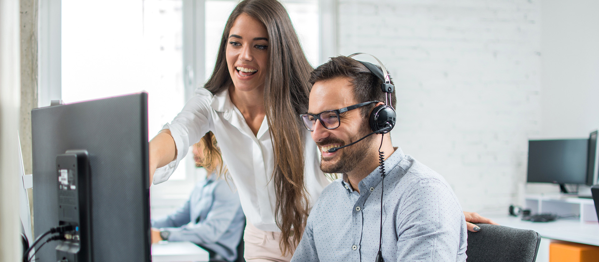 Zusammenarbeit Mann und Frau an Computer mit Headset