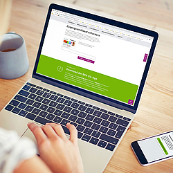 Eine Frau sitzt an einem Laptop. Auf dem Bildschirm ist die Internetseite der BKK GS. Auf dem Tisch liegt ihr Smartphone mit der BKK GS App.