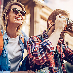 Pärchen im Urlaub mit Sonnenbrille und Kamera.