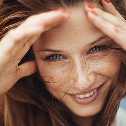 Frau lächelt und fährt sich durch die Haare.
