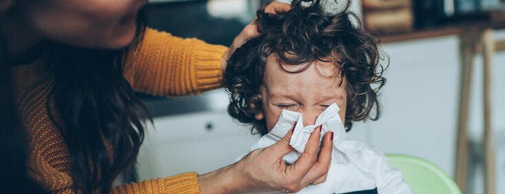 Mutter hilft krankem Kind beim Nase Putzen