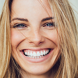 Blonde Frau mit strahlendem Lächeln.