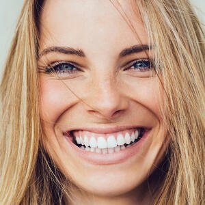 blonde Frau lächelt mit Zähnen 