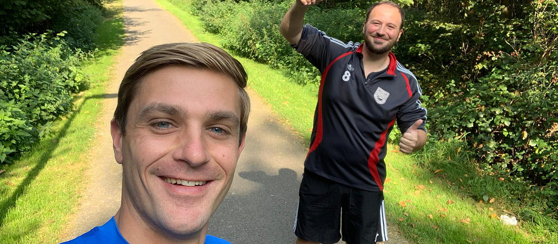Radiomoderatoren von Radio Bielefeld Tom Schütz und Sebastian Wiese in Sportkleidung. Tom Schütz macht ein Selfie von den beiden, Sebastian Wiese hält ein Mikrofon hoch.