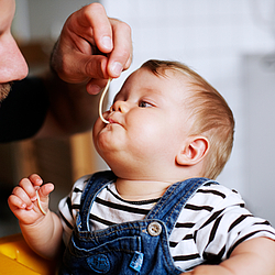 Ein Vater hilft seinem kleinen Sohn beim Essen.
