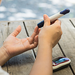 Eine Frau sticht sich mit einem Messgerät in den Finger, um ihren Blutzuckerspiegel zu ermitteln.