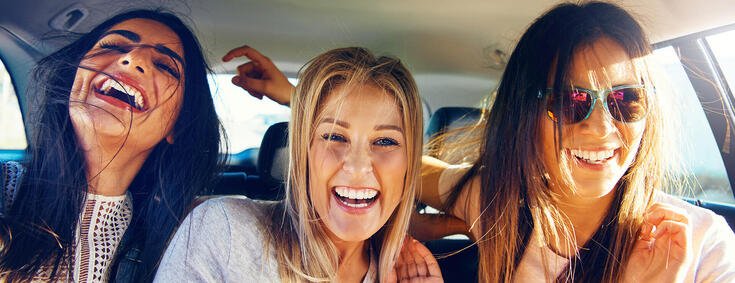 Drei glückliche Frauen auf der Rückbank eines Autos