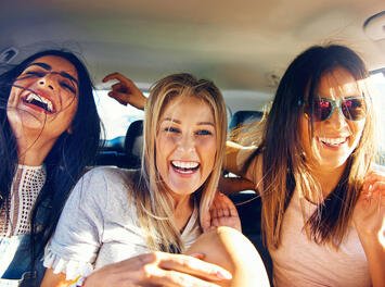 drei junge Frauen lachen im Auto