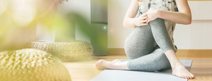 Frau macht Yoga-Pose in Wohnzimmer