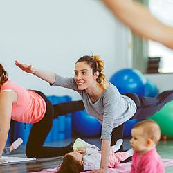 Eine Gruppe junger Mütter besucht einen Sportkurs. Die Mütter haben ihre Babys dabei.
