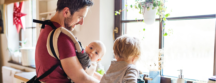 Mann betreut seine beiden Kinder und macht gleichzeitig Küchenarbeit