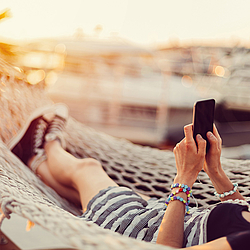 Frau in Hängematte mit Smartphone.