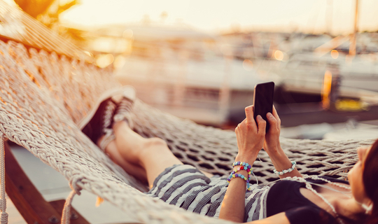 frau in hängematte mit smartphone