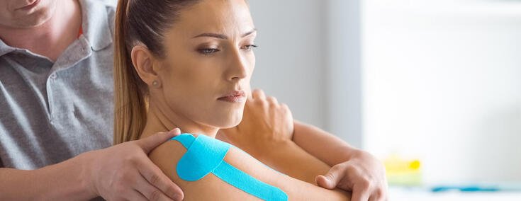 Frau bekommt Behandlung beim Physiotherapeuten mit Kinesio-Tape