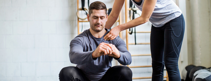 Mann bekommt persönliches Training von Trainerin zu Rehabilitation