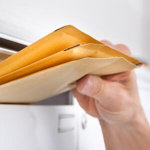 Hand entnimmt Briefe aus Briefkasten