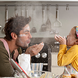 Vater und Tochter backen in der Küche und albern dabei herum. 