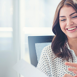 Eine Frau mit langen braunen Haaren lacht freundlich. Sie ist im Gespräch mit einem Mann.