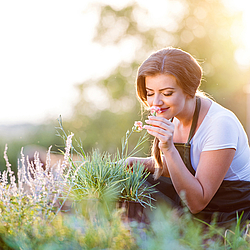 Frau im Garten riecht an Kräutern.