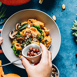 Ein Teller mit einem Gericht aus Nudeln, Pilzen und anderen gesunden Zutaten.