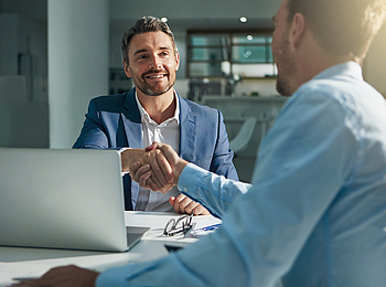 Zwei Männer sind bei einem Geschäftstreffen und geben sich die Hand.
