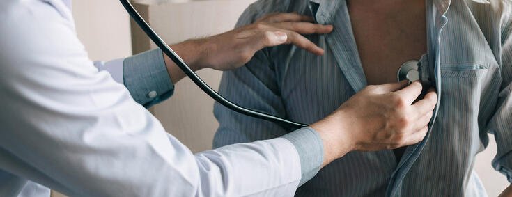 Ärztin untersucht Mann mit Stethoskop