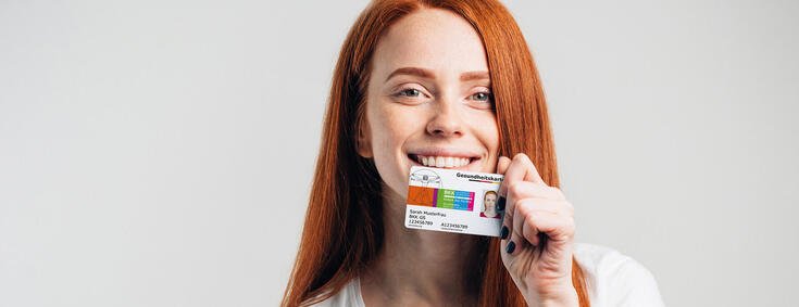 Junge Frau hält glücklich ihre neue Gesundheitskarte