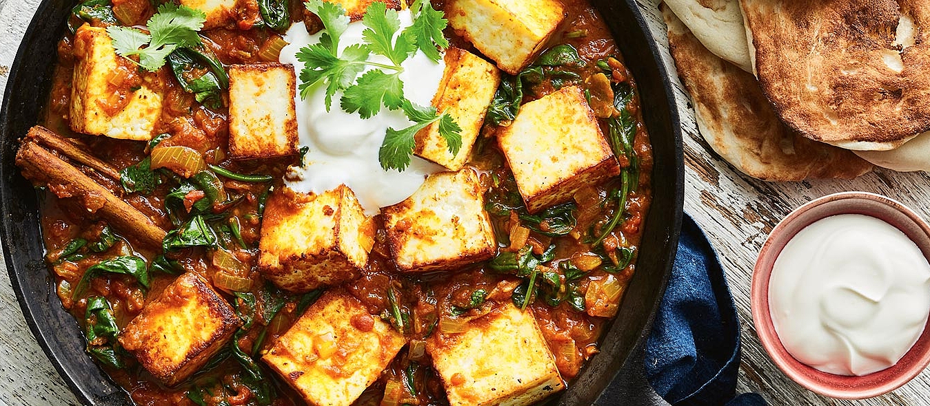 Paneer-Spinat-Tikka-Masala mit gebratenen Paneerwürfeln, Joghurt und Naanbrot.