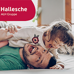 Vater und seine kleine Tochter toben auf dem Boden. Beiden lachen.