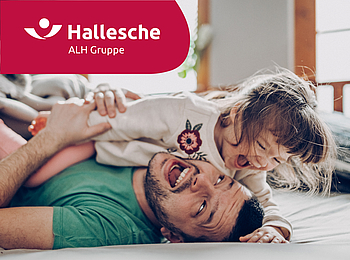 Vater und seine kleine Tochter toben auf dem Boden. Beiden lachen.