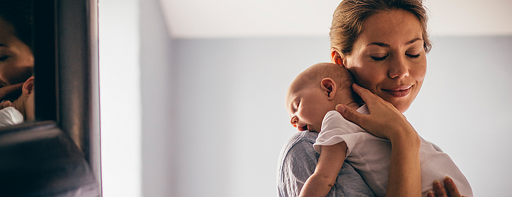 Mutter hält fürsorglich ihr Baby auf dem Arm