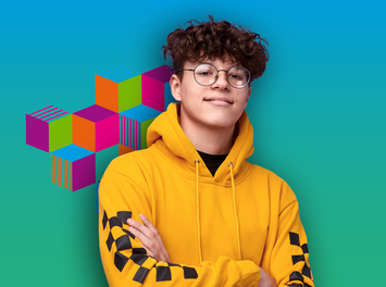 Ein junger Mann mit braunen lockigen Haaren und Brille lacht in die Kamera. Er trägt einen gelben Pullover. 
