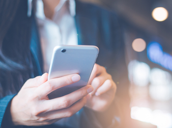 Eine junge Frau schaut auf ihr Smartphone.