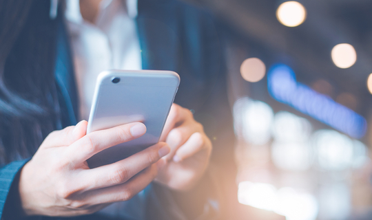 Eine junge Frau schaut auf ihr Smartphone.
