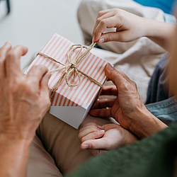 Zwei Personen verpacken gemeinsam ein Geschenk.