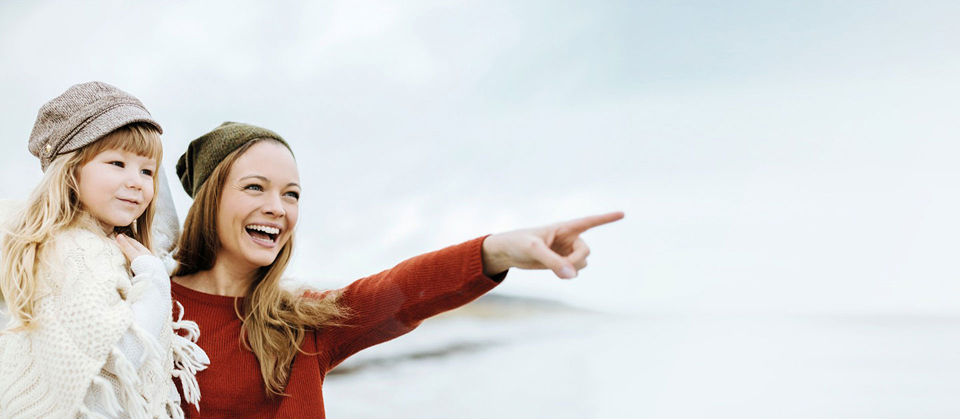 langhaarige Frau zeigt kleinem Mädchen etwas in der Ferne