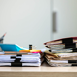 Auf einem Tisch liegen Aktenstapel.