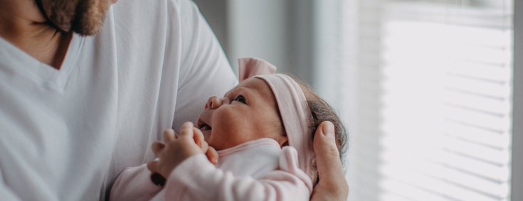 Vater hält glücklich neugeborenes Baby im Arm