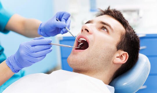Mann mit offenem Mund wird beim Zahnarzt behandelt