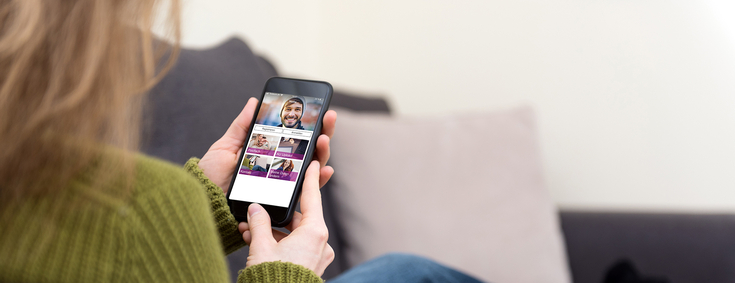 BKK GS App Frau auf Sofa benutzt die BKK GS-App auf ihrem Smartphone