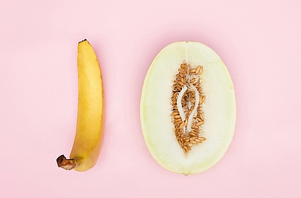 Banane und halbierte Honigmelone liegen nebeneinander auf rosafarbenem Hintergrund.
