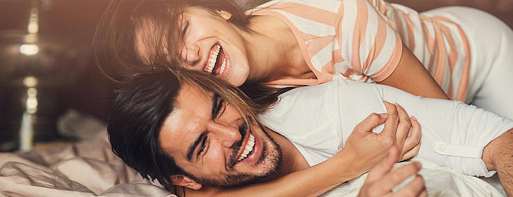 Frau umarmt Mann glücklich von hinten