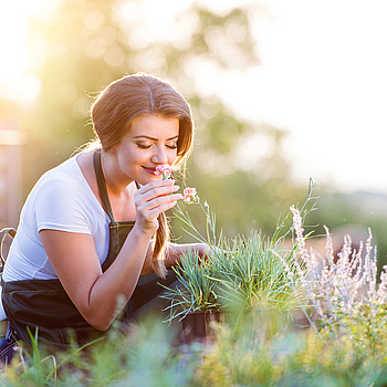 frau im garten riecht an kräutern