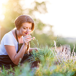 Frau im Garten riecht an Kräutern.