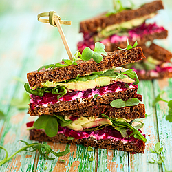 Ein gesundes Sandwich belegt mit Salat, Avocado und roter Beete.