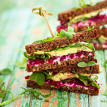 Ein gesundes Sandwich belegt mit Salat, Avocado und roter Beete.