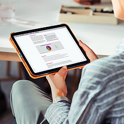 Frau hält ein Tablet in der Hand und liest dort das BKK Service Magazin.