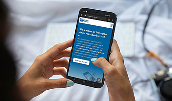 Eine Frau nutzt ihr Smartphone. Sie stellt eine Anfrage bei "Online Doctor".