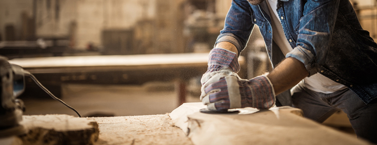 Mann hobelt Holz in einer Werkstatt